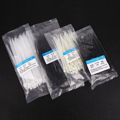Bolsas de bridas de nylon blancas y negras para organizar cables sobre fondo negro.
